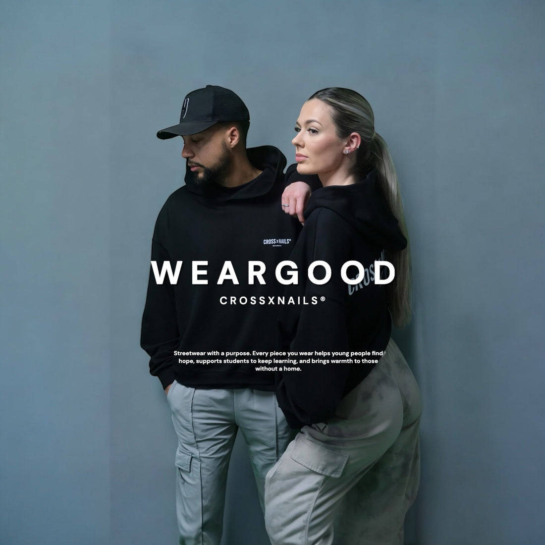 Two models wearing Crossxnails® black hoodies with ‘WEARGOOD’ text. Streetwear with a purpose to support youth, students, and the homeless.