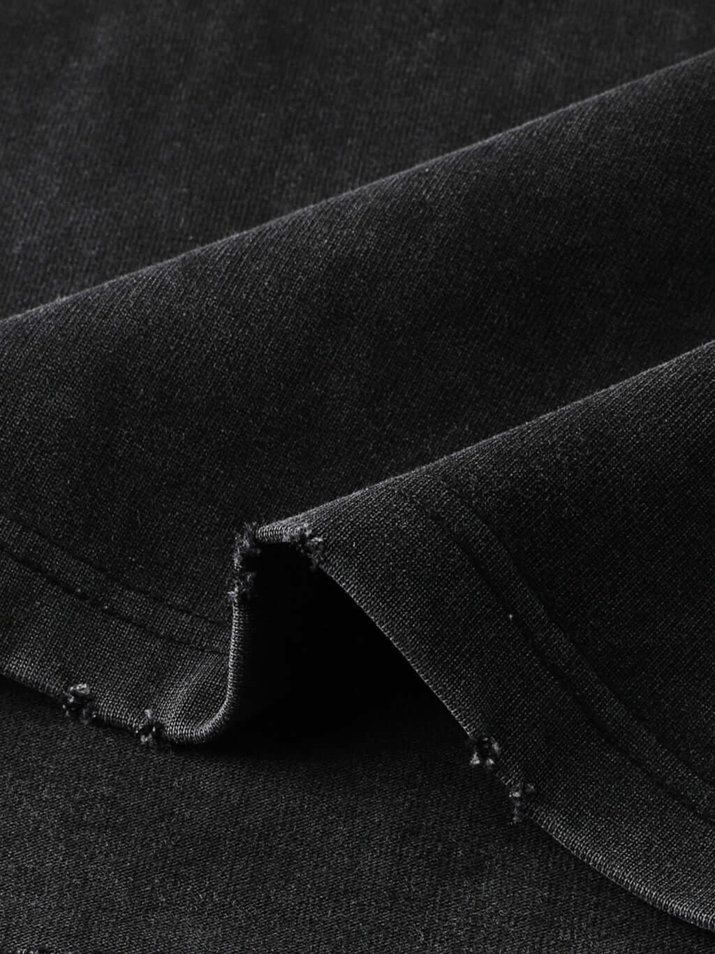Close-up of textured black fabric showcasing raw-edge hem detail of Crossxnails Heavyweight T-Shirt, premium oversized style.